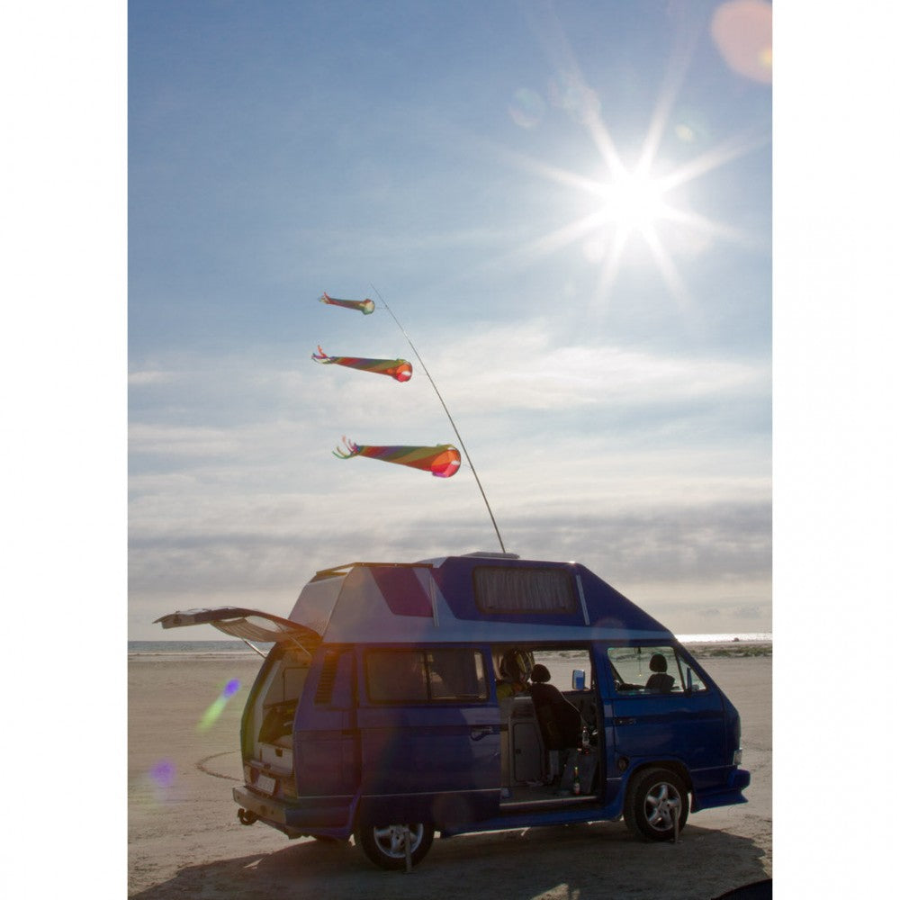 En autocamper er stillet klar på stranden med tre vinddragere på taget