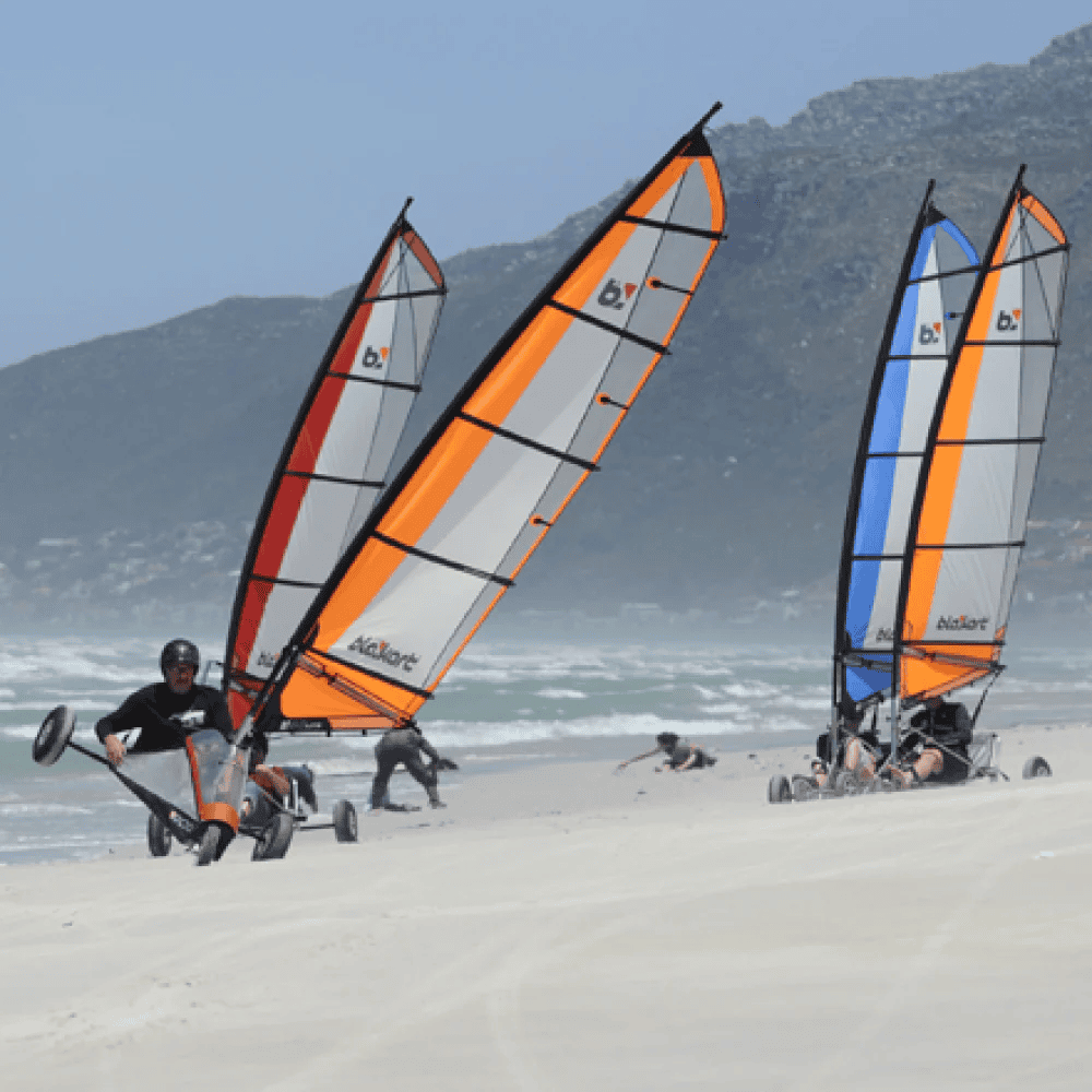 Fire personer køre blokart på en strand.