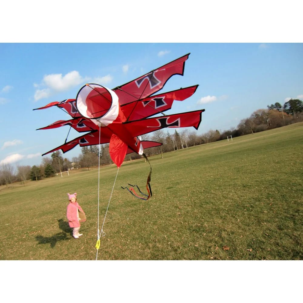 X Kites 3D Red Baron er blevet sat i luften. Et lille barn kigger beundrende på den røde baron.